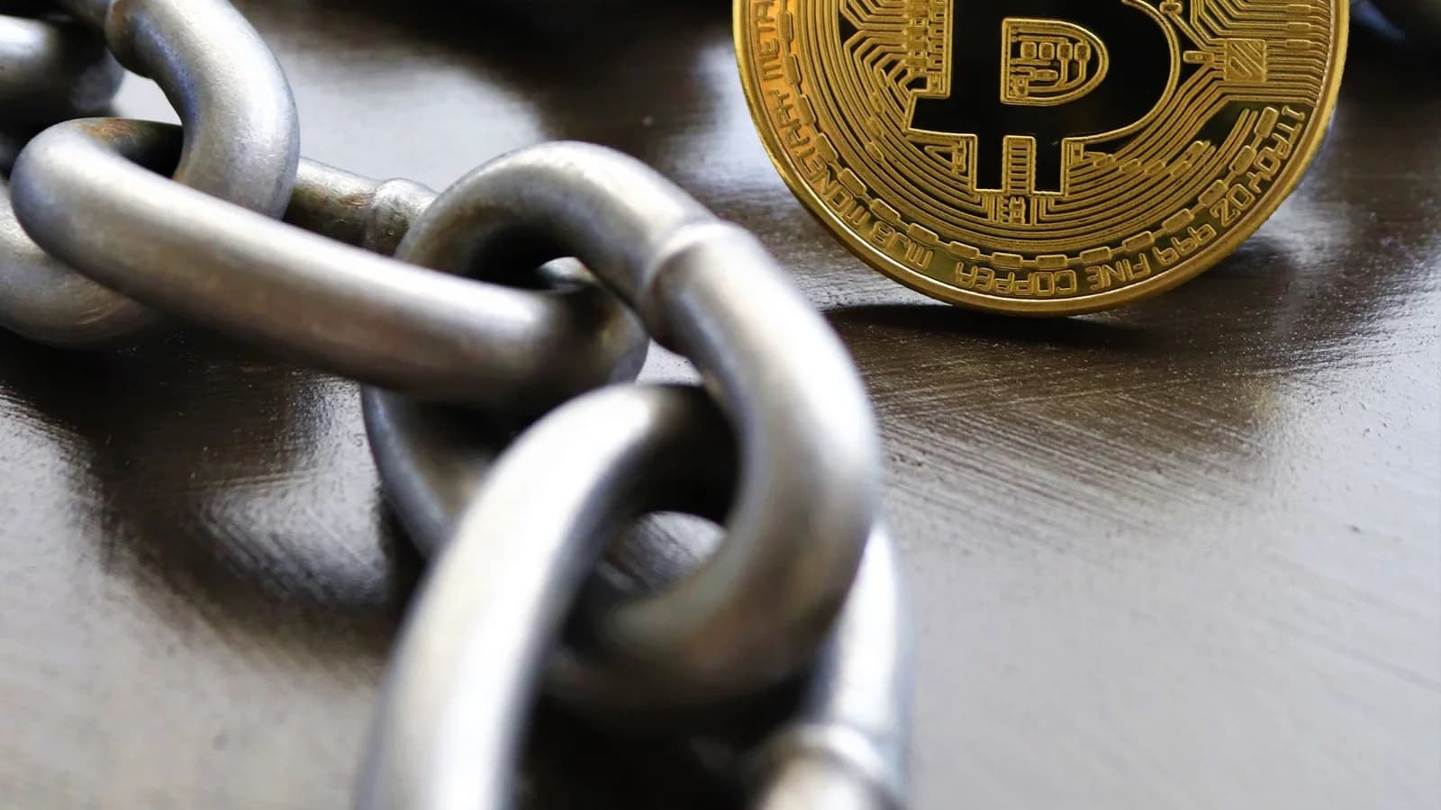 Bitcoin coins intertwined with a metal chain, symbolizing cryptocurrency and blockchain security.