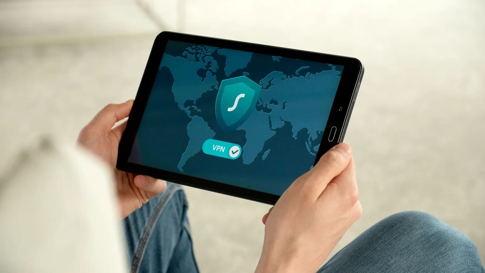Person holding a tablet displaying a digital security shield. Photo: Pexels.