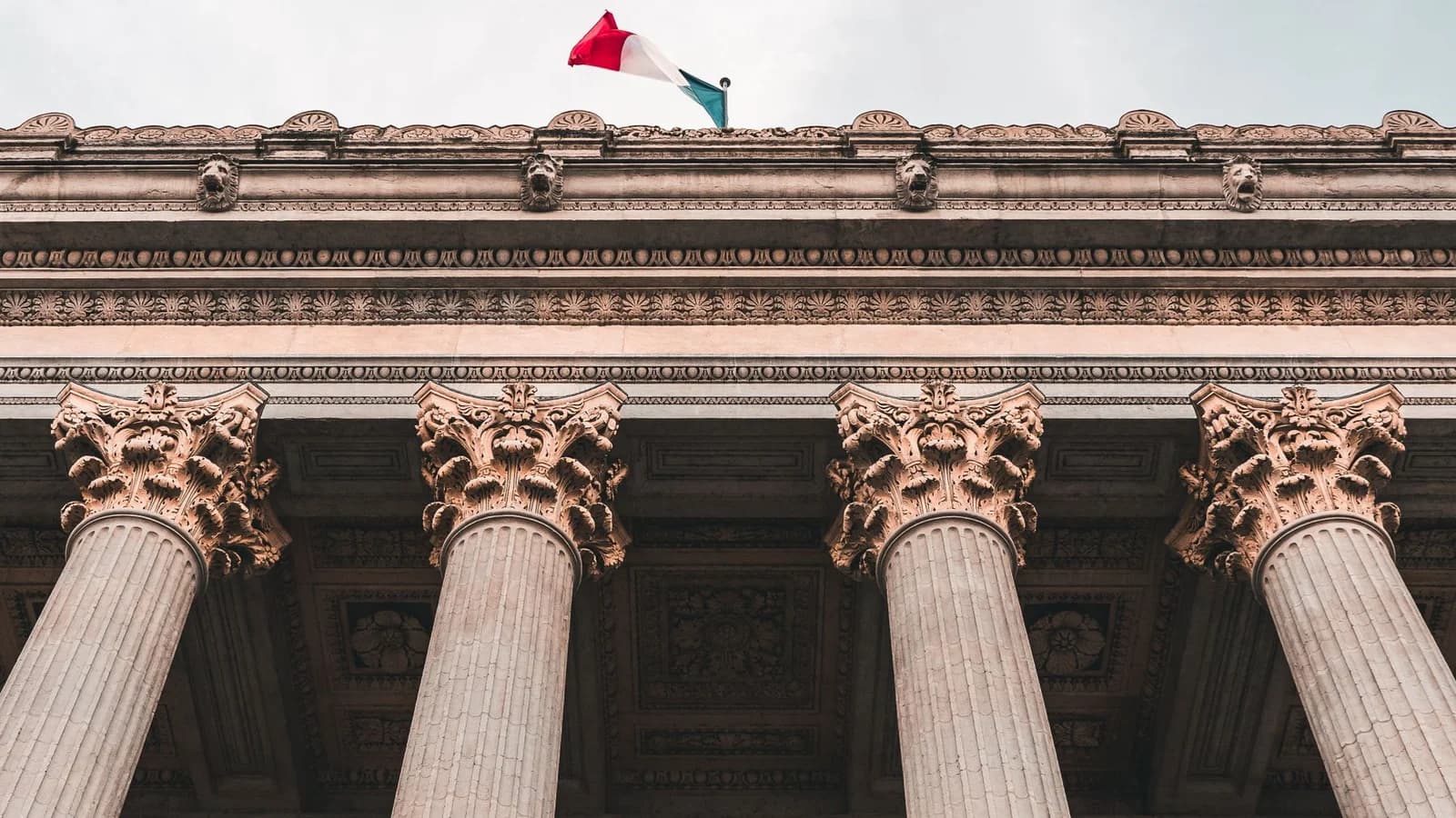 Low-angle view of a historic courthouse with columns and French flag in Lyon, France.