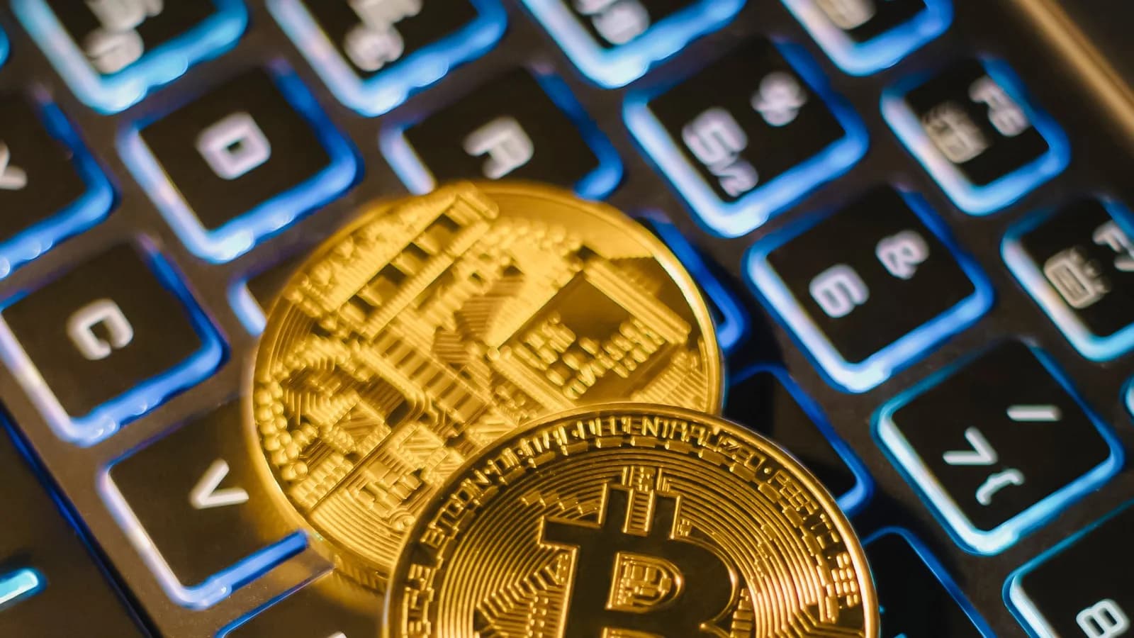 Bitcoin coins resting on an illuminated keyboard